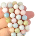 Koraliki z naturalnego morganitu w pastelowych odcieniach różu, błękitu, zieleni i beżu, w kształcie gładkich kul o średnicy około 8 mm, nawleczone na sznurki. Półprodukty do własnoręcznego wyrobu biżuterii