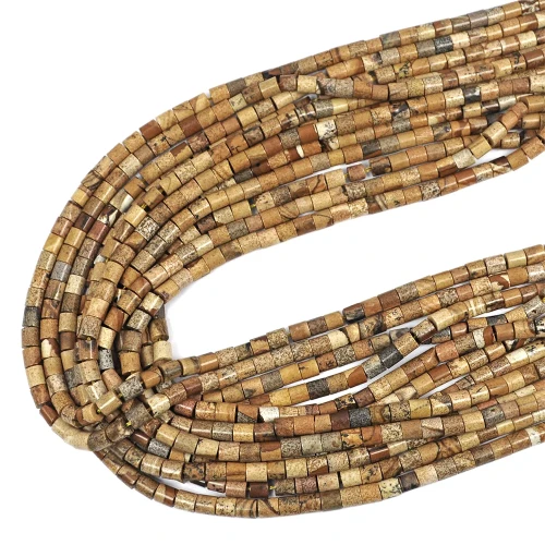 Kamienie w formie gładkich walców z jaspisu obrazkowego, o wymiarach ok. 4 × 4,5 mm. Nawleczone na żółte sznurki.  Ujęcie z góry – leżą w zwiniętej kiści na białym tle.