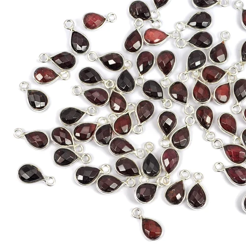 Zawieszki z naturalnym granatem w formie kropli fasetowanej ok.11x6 mm, oprawione w srebro 925, idealne do naszyjników i bransoletek, ujęcie z góry, leżące luzem na białym tle