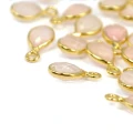 Zawieszki z naturalnym kwarcem różowym w formie kropli fasetowanej ok.11x6 mm, oprawione w srebro pozłacane 925, idealne do naszyjników i bransoletek, widok z perspektywy bocznej, leżące luzem na białym tle