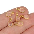 Zawieszki z naturalnym kwarcem różowym w formie kropli fasetowanej ok.11x6 mm, oprawione w srebro pozłacane 925, idealne do naszyjników i bransoletek, prezentowane na dłoni, na białym tle