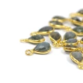 Zawieszki z naturalnym labradorytem w formie kropli fasetowanej ok.11x6 mm, oprawione w srebro pozłacane 925, idealne do naszyjników i bransoletek, widok z perspektywy bocznej, leżące luzem na białym tle