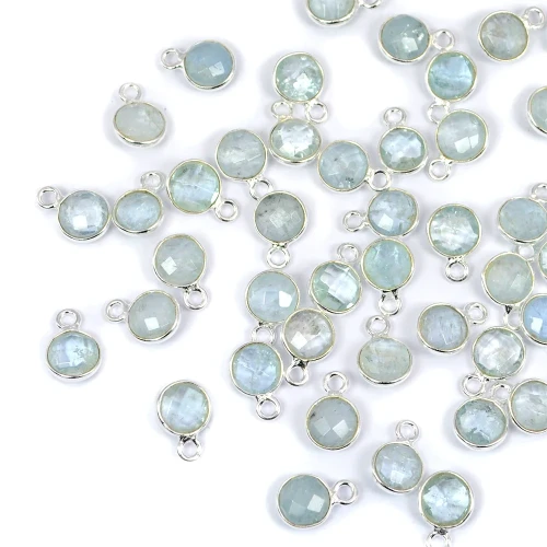 Okrągłe, fasetowane zawieszki z akwamarynu błękitnego, ok.10x7 mm, oprawione w srebro 925, idealne do naszyjników i bransoletek, ujęcie z góry, leżące luzem na białym tle.
