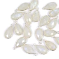 Zawieszki w kształcie kropli fasetowanej, z naturalnym kamieniem księżycowym o wymiarach ok.20x10 mm, oprawione w srebro 925, idealne do naszyjników i bransoletek, ujęcie z góry, leżące luzem na białym tle